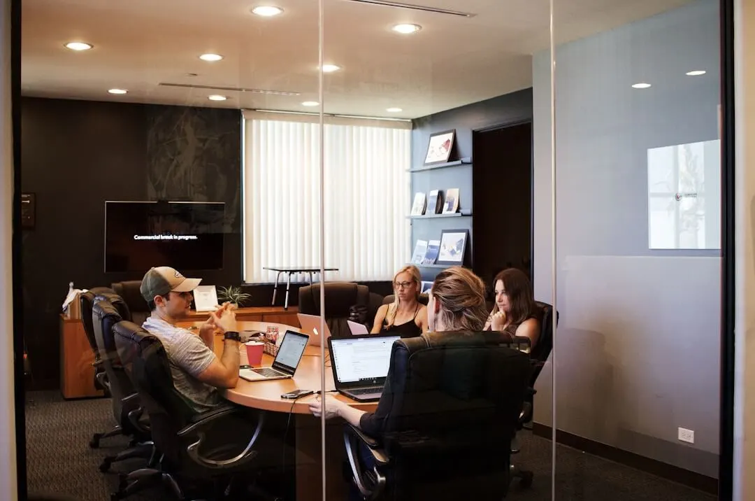 Employees in a conference room discussing proposal management tools and their role in streamlining sales