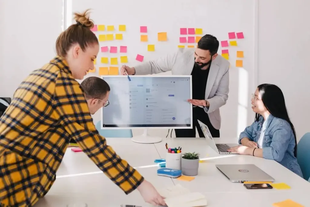 Team members in a conference room reviewing a side-by-side comparison of key features in Qvidian vs. Responsive